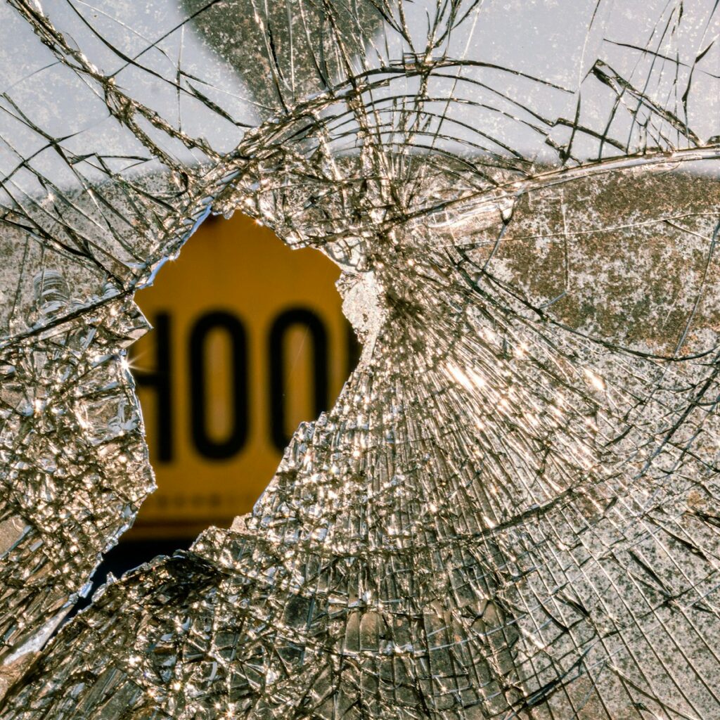 a broken glass window with a yellow sign on it